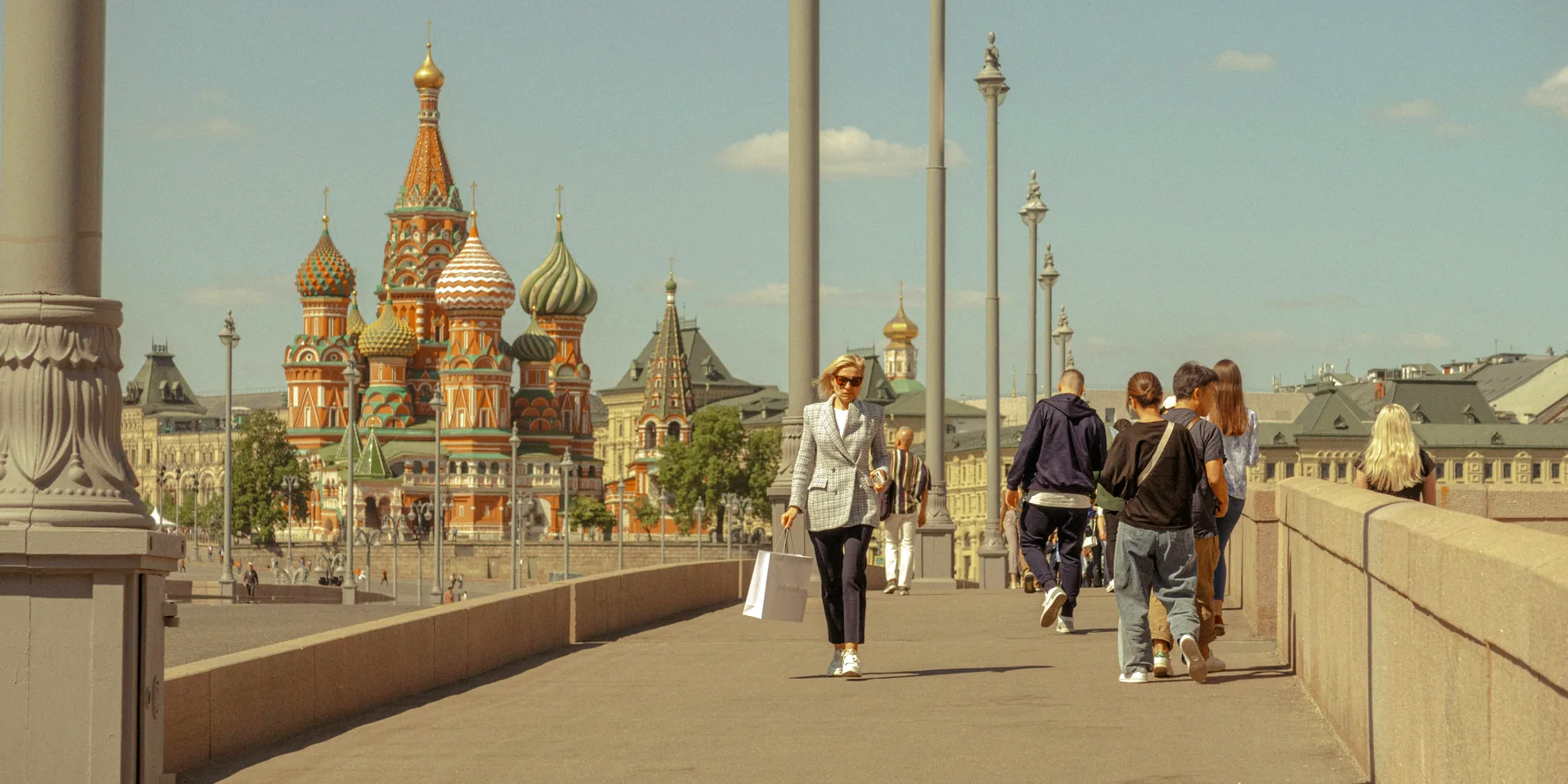 Люди идут по мосту к храму Василия Блаженного в Москве